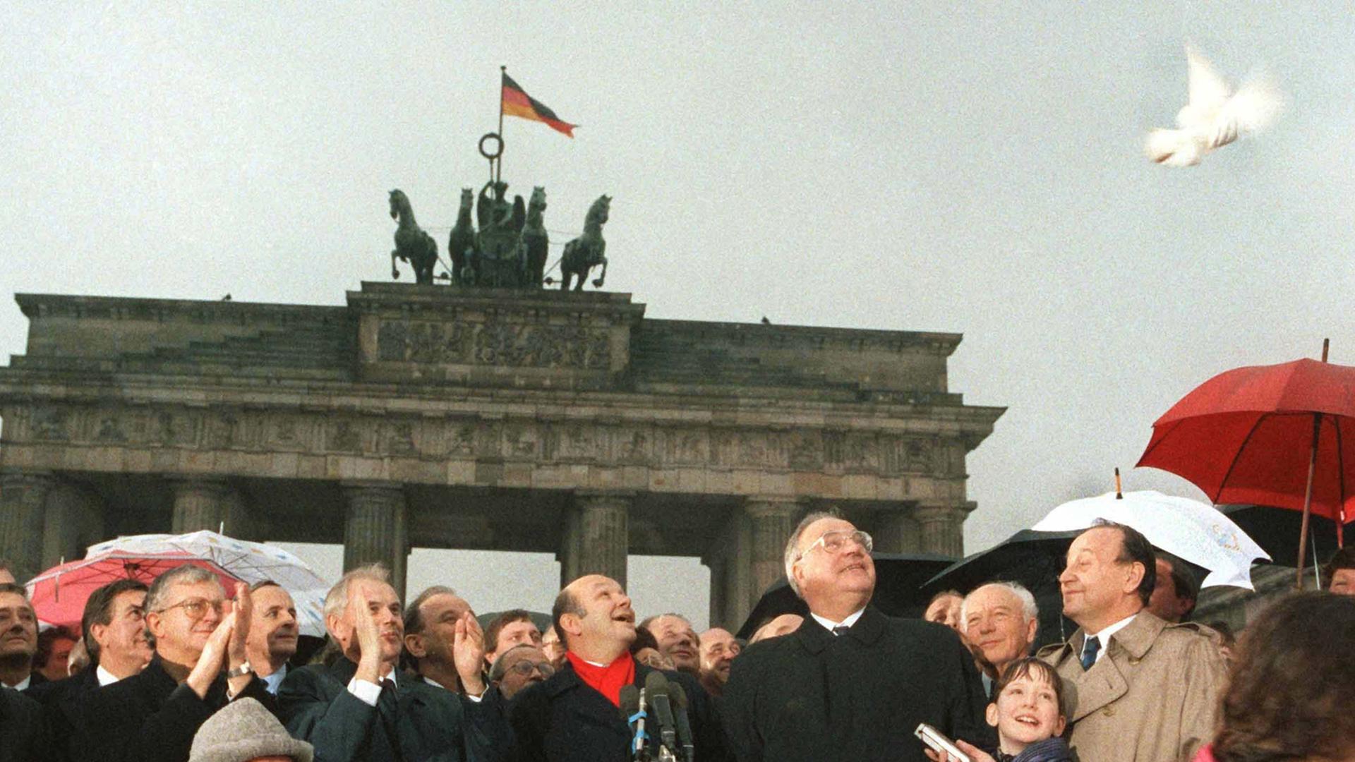 28 Jahre nach dem Mauerbau ist das Brandenburger Tor wieder zugänglich: DDR-Ministerpräsident Hans Modrow und Bundeskanzler Helmut Kohl lassen am 22. Dezember 1989 Friedenstauben aufsteigen. In der Mitte Walter Momper, Regierender Bürgermeister von Berlin. 28 Jahre nach dem Mauerbau ist das Brandenburger Tor wieder zugänglich: DDR-Ministerpräsident Hans Modrow und Bundeskanzler Helmut Kohl lassen am 22. Dezember 1989 Friedenstauben aufsteigen. In der Mitte Walter Momper, Regierender Bürgermeister von Berlin.