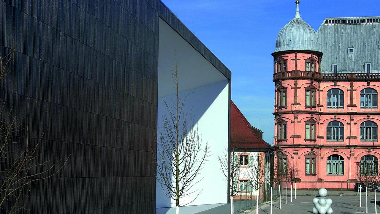 Ein Neubau mit kantigen Ecken steht neben dem historischen Haus mit Fassadenschmuck. Ein Neubau mit kantigen Ecken steht neben dem historischen Haus mit Fassadenschmuck.