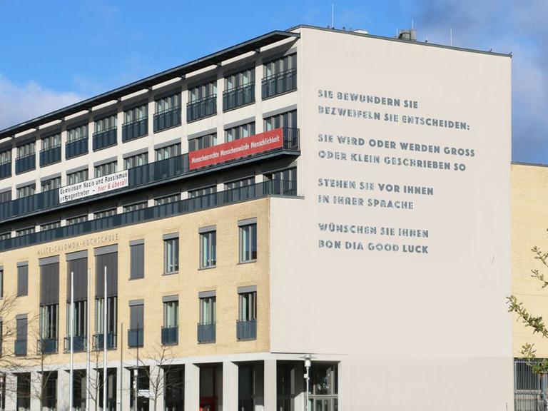 Fotomontage: Das Gedicht von Barbara Köhler nach der Fassadensanierung an der ASH Berlin, es lautet "SIE BEWUNDERN SIE / BEZWEIFELN SIE ENTSCHEIDEN: / SIE WIRD ODER WERDEN GROSS / ODER KLEIN GESCHRIEBEN SO / STEHEN SIE VOR IHNEN / IN IHRER SPRACHE / WÜNSCHEN SIE IHNEN / BON DIA GOOD LUCK