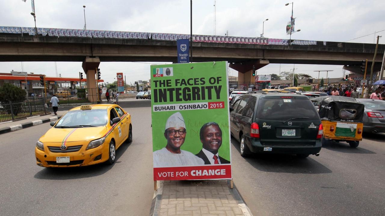 Autos fahren am 14.02.2015 an einem Wahlplakat in Lagos, Nigeria vorbei. Das Plakat zeigt den Präsitentschaftskandidaten Muhammadu Buhari (L) und Vize-Kandidat Yemi Osinbajo (R). Autos fahren am 14.02.2015 an einem Wahlplakat in Lagos, Nigeria vorbei. Das Plakat zeigt den Präsitentschaftskandidaten Muhammadu Buhari (L) und Vize-Kandidat Yemi Osinbajo (R).