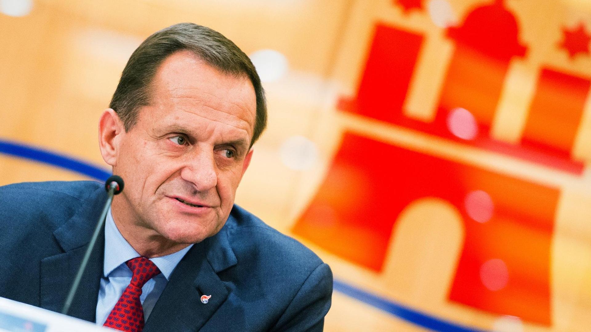 Alfons Hörmann sitzt vor einem Mikrofon.