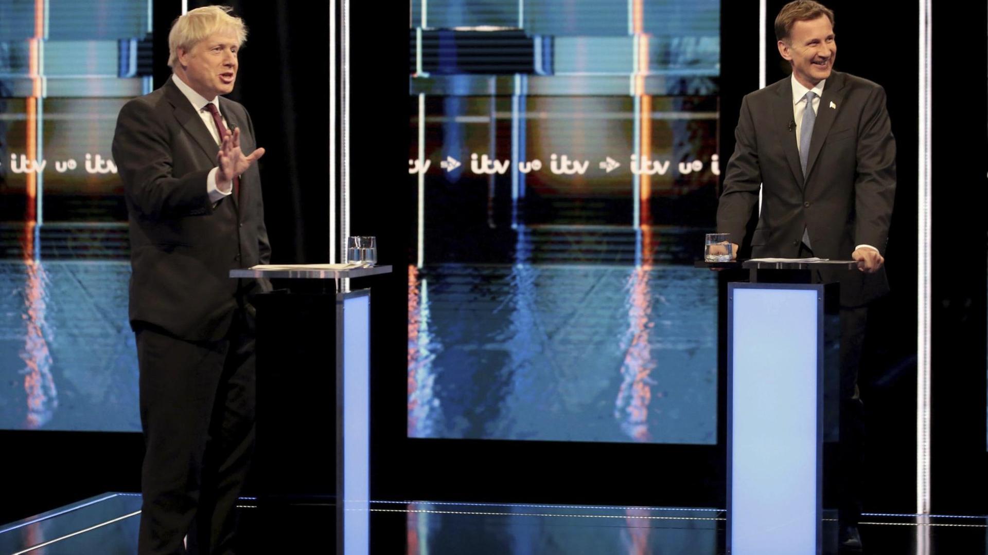 Boris Johnson und Jeremy Hunt stehen sich an Rednerpulten im Fernsehstudio gegenüber. Boris Johnson und Jeremy Hunt stehen sich an Rednerpulten im Fernsehstudio gegenüber.