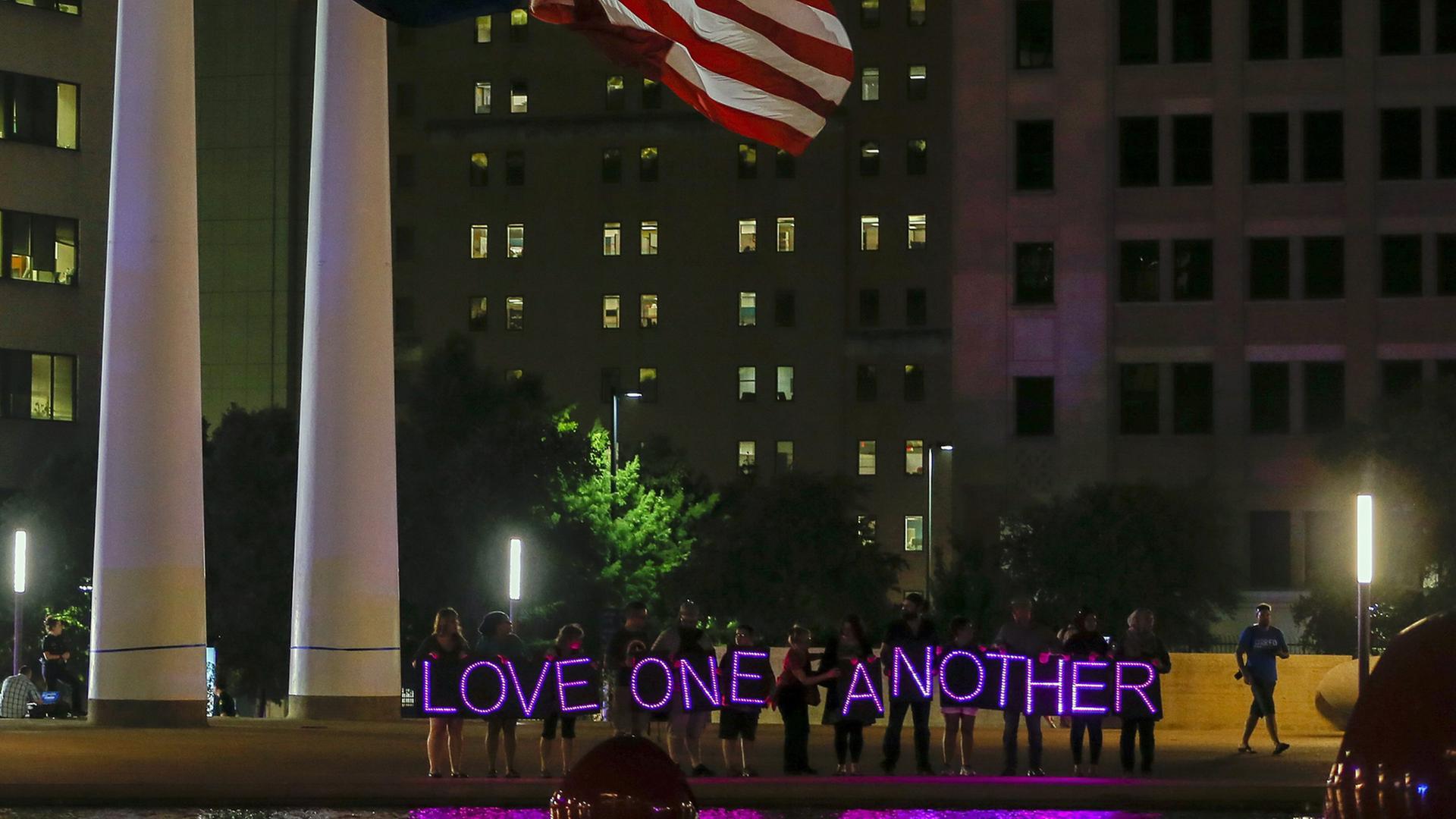 Menschen halten bei einer Nachtwache auf dem Platz vor der City Hall in Dallas LED-Lichter mit dem Schriftzug "Love one another" - liebt einander - hoch, aufgenommen am 11. Juli 2016. Menschen halten bei einer Nachtwache auf dem Platz vor der City Hall in Dallas LED-Lichter mit dem Schriftzug "Love one another" - liebt einander - hoch, aufgenommen am 11. Juli 2016.