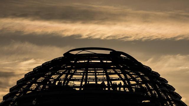 Besucher stehen in der Kuppel des Reichstags, aufgenommen während des Sonnenuntergangs.