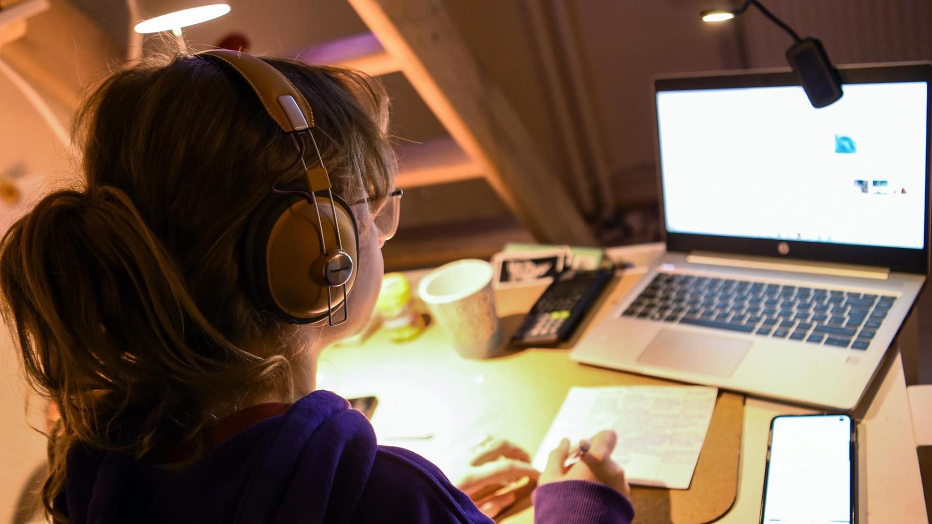 Ein Mädchen sitzt zu Hause an ihrem Schreibtisch und macht an ihrem Laptop Aufgaben für die Schule. Ein Mädchen sitzt zu Hause an ihrem Schreibtisch und macht an ihrem Laptop Aufgaben für die Schule.