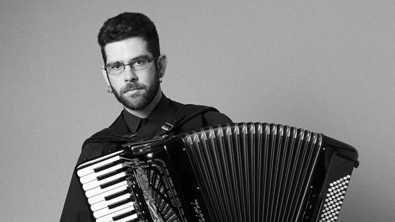 Der Musiker sitzt mit seinem weit ausgezogenen Akkordeon auf einem Hocker Der Musiker sitzt mit seinem weit ausgezogenen Akkordeon auf einem Hocker