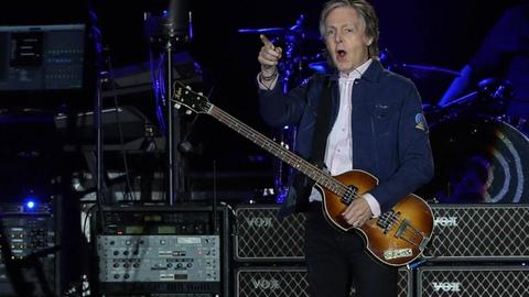 Paul McCartney steht mit Bass auf der Bühne und zeigt ins Publikum.