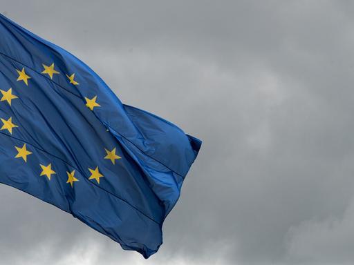 Die Flagge der Europäischen Union weht vor wolkenverhangenem Himmel.