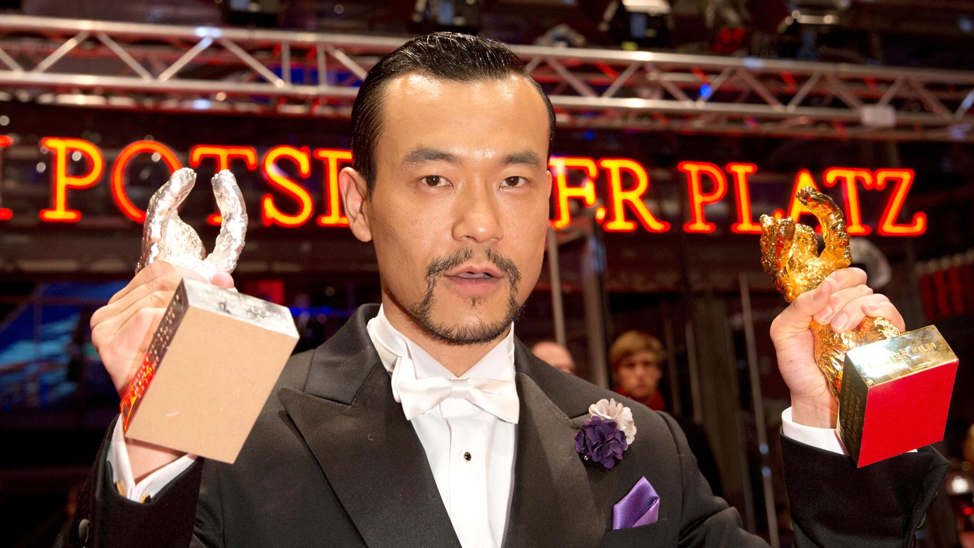 Der chinesische Schauspieler Fan Liao ("Bai Ri Yan Huo"/ "Feuerwerk am helllichten Tage") posiert am während der 64. Internationalen Filmfestspiele in Berlin mit dem Goldenenen und Silbernen Bären. Liao wurde mit dem Silbernen Bären als bester Darsteller ausgezeichnet, der Film gewann den Goldenen Bären.