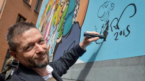 Comiczeichner Ralf König signiert in Brüssel eine von ihm gemachte Wandmalerei.