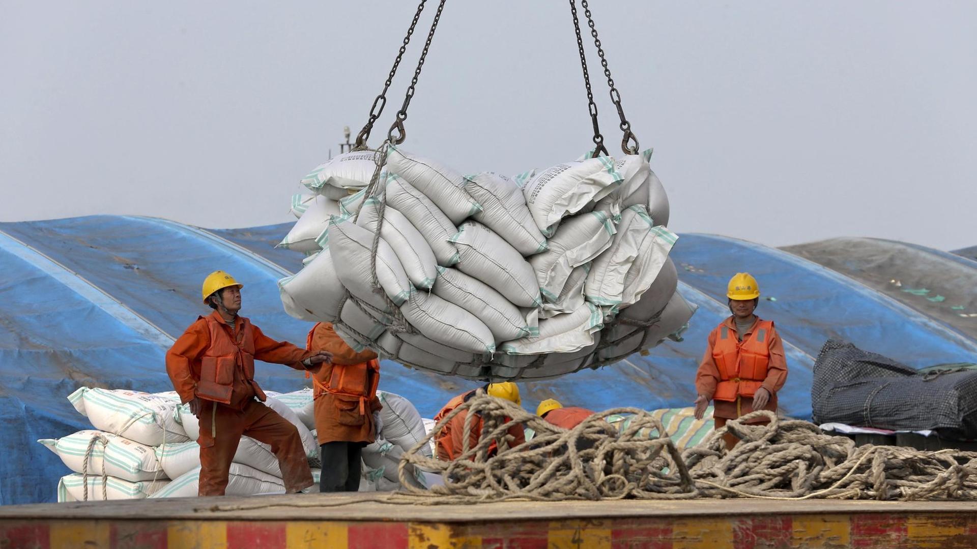 Arbeiter verladen im Hafen von Nantong (China) Säcke mit importierten Sojabohnen. Arbeiter verladen im Hafen von Nantong (China) Säcke mit importierten Sojabohnen.