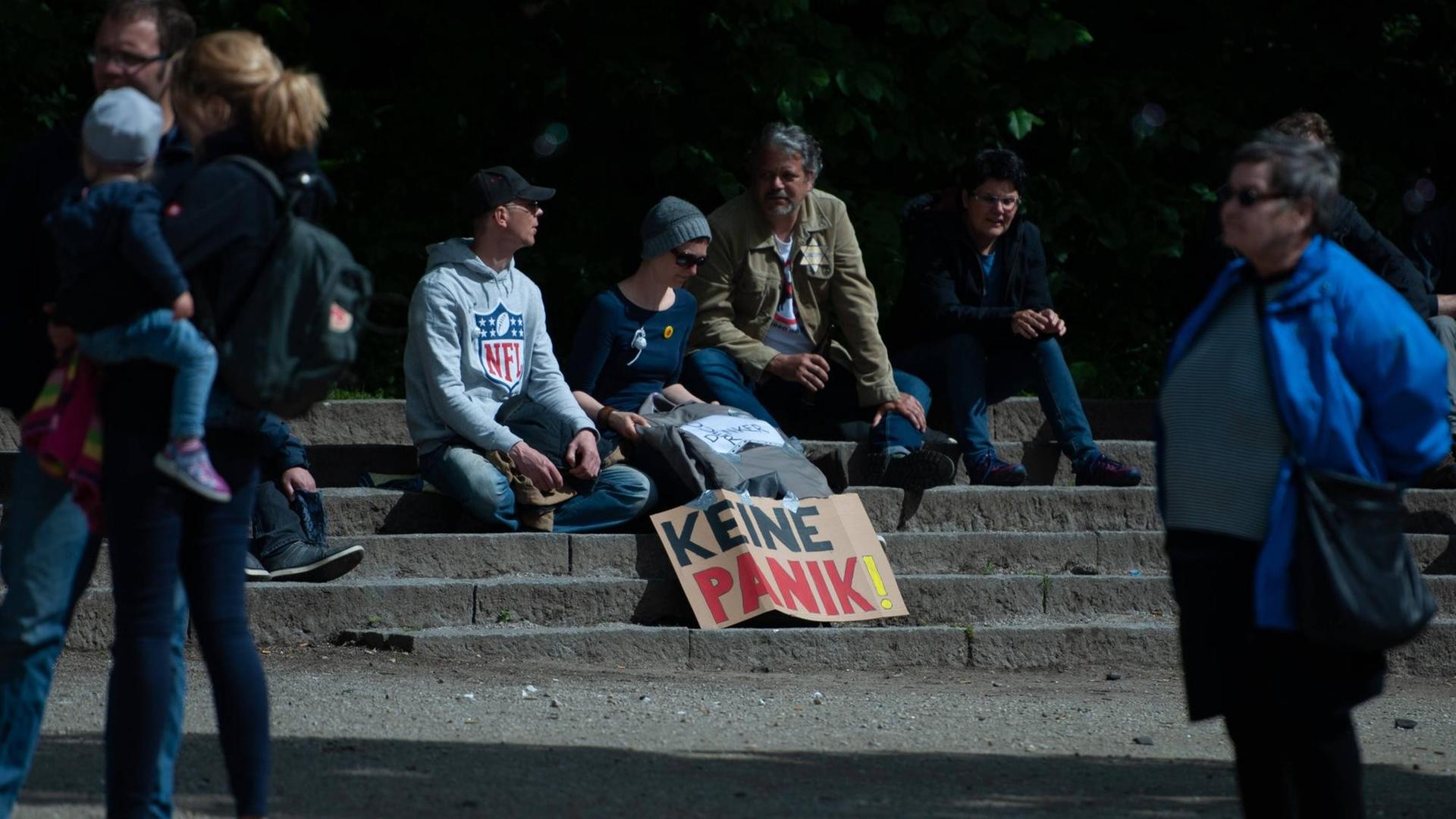 Bei einer Demonstration gegen Corona-Maßnahmen: Vier Demonstranten sitzen auf Steinstufen, vor sich ein Transparent mit der Aufschrift "Keine Panik". Win Demonstrant hat einen gelben Stern auf der Jacke. Auf diesem steht "Ungeimpft". Bei einer Demonstration gegen Corona-Maßnahmen: Vier Demonstranten sitzen auf Steinstufen, vor sich ein Transparent mit der Aufschrift "Keine Panik". Win Demonstrant hat einen gelben Stern auf der Jacke. Auf diesem steht "Ungeimpft".