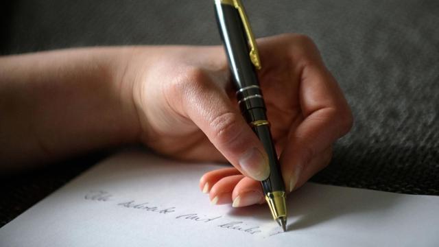 Die Hand einer Frau mit Kugelschreiber setzt ein Ausrufezeichen hinter den Satz: "Ich schreibe mit links".