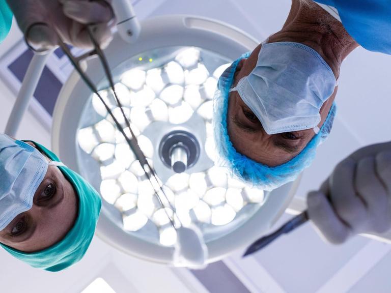 Zwei Ärzte beugen sich unter typischen Op-Strahlern über den möglichen Patienten.