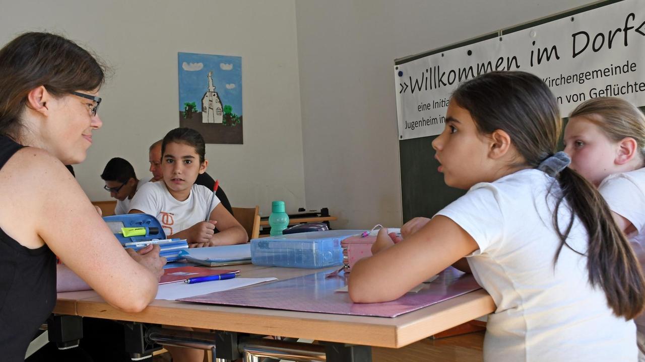 Eine Integrationsfachkraft hilft Kindern bei den Hausaufgaben. Eine Integrationsfachkraft hilft Kindern bei den Hausaufgaben.
