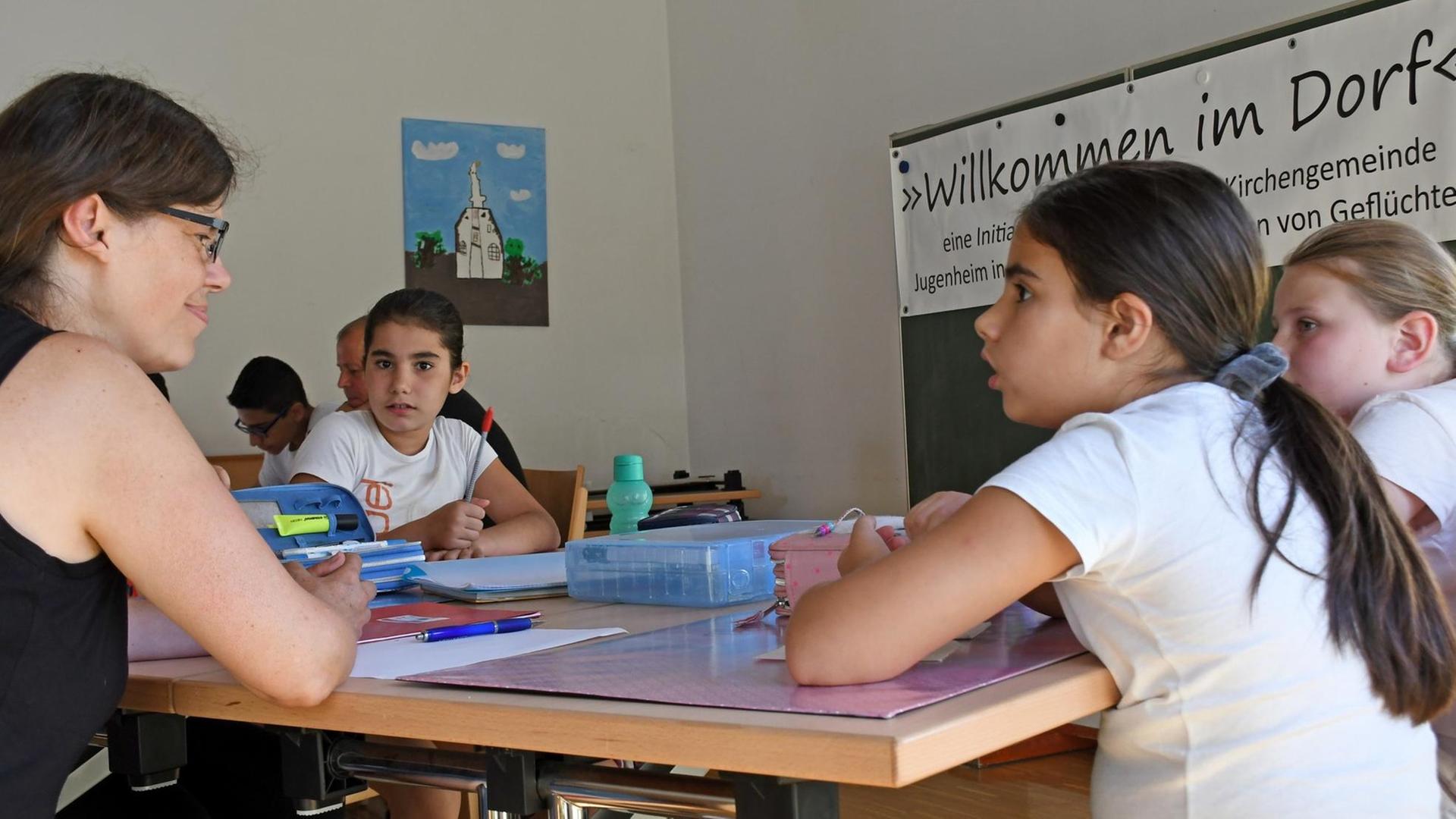 Eine Integrationsfachkraft hilft Kindern bei den Hausaufgaben.