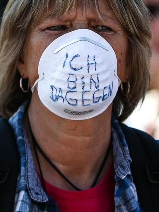 "Ich bin dagegen" steht auf der Schutzmaske einer Frau geschrieben, die an der dritten Demonstration der "Querdenken"-Initiative auf dem Stuttgarter Schlossplatz teilnimmt