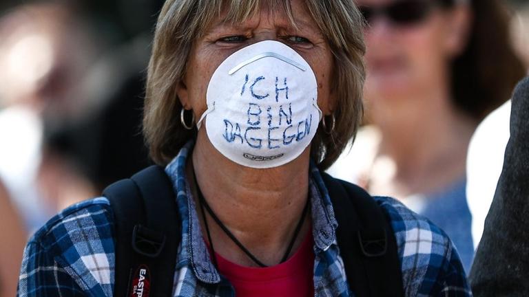 "Ich bin dagegen" steht auf der Schutzmaske einer Frau geschrieben, die an der dritten Demonstration der "Querdenken"-Initiative auf dem Stuttgarter Schlossplatz teilnimmt