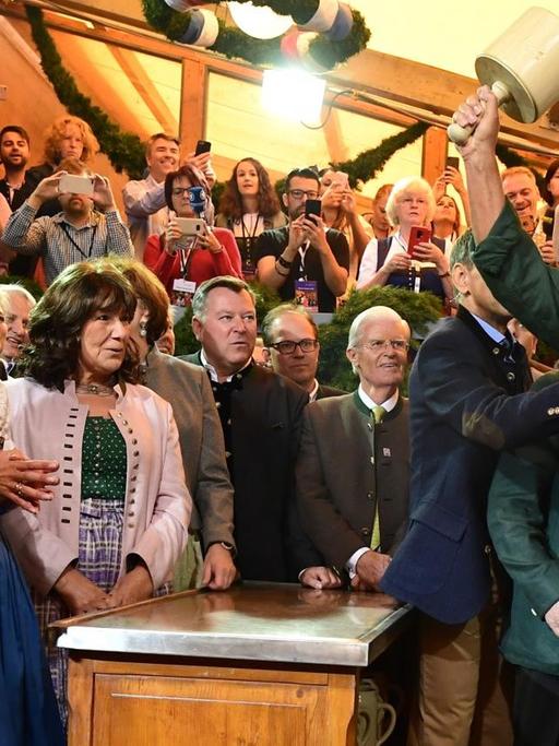 Markus Söder, Ministerpräsident von Bayern, und seine Frau Karin Baumüller-Söder schauen Dieter Reiter (SPD), Oberbürgermeister von München beim traditionellen Fassanstich zu.
