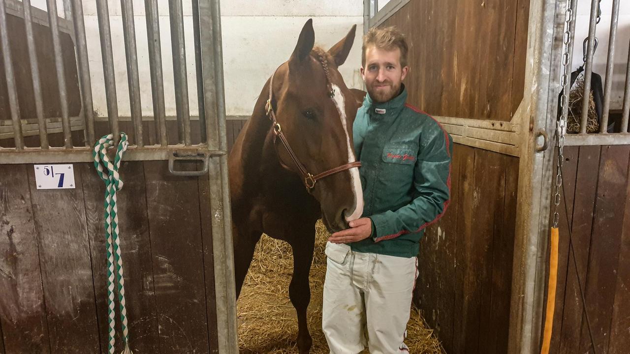 Jockey Victor Gentz im Stall neben einem Pferd. Jockey Victor Gentz im Stall neben einem Pferd.