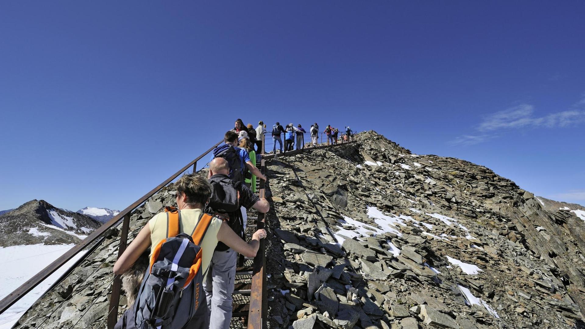 Viele Touristen laufen hintereinander zur Aussichtsplattform "Top of Tyrol" in den Stubauer Alpen hinauf