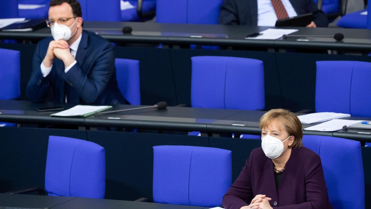 Jens Spahn (l, CDU), Bundesgesundheitsminister, und Bundeskanzlerin Angela Merkel (CDU) sitzen bei der Aktuellen Stunde in der Plenarsitzung im Deutschen Bundestag auf der Regierungsbank. 