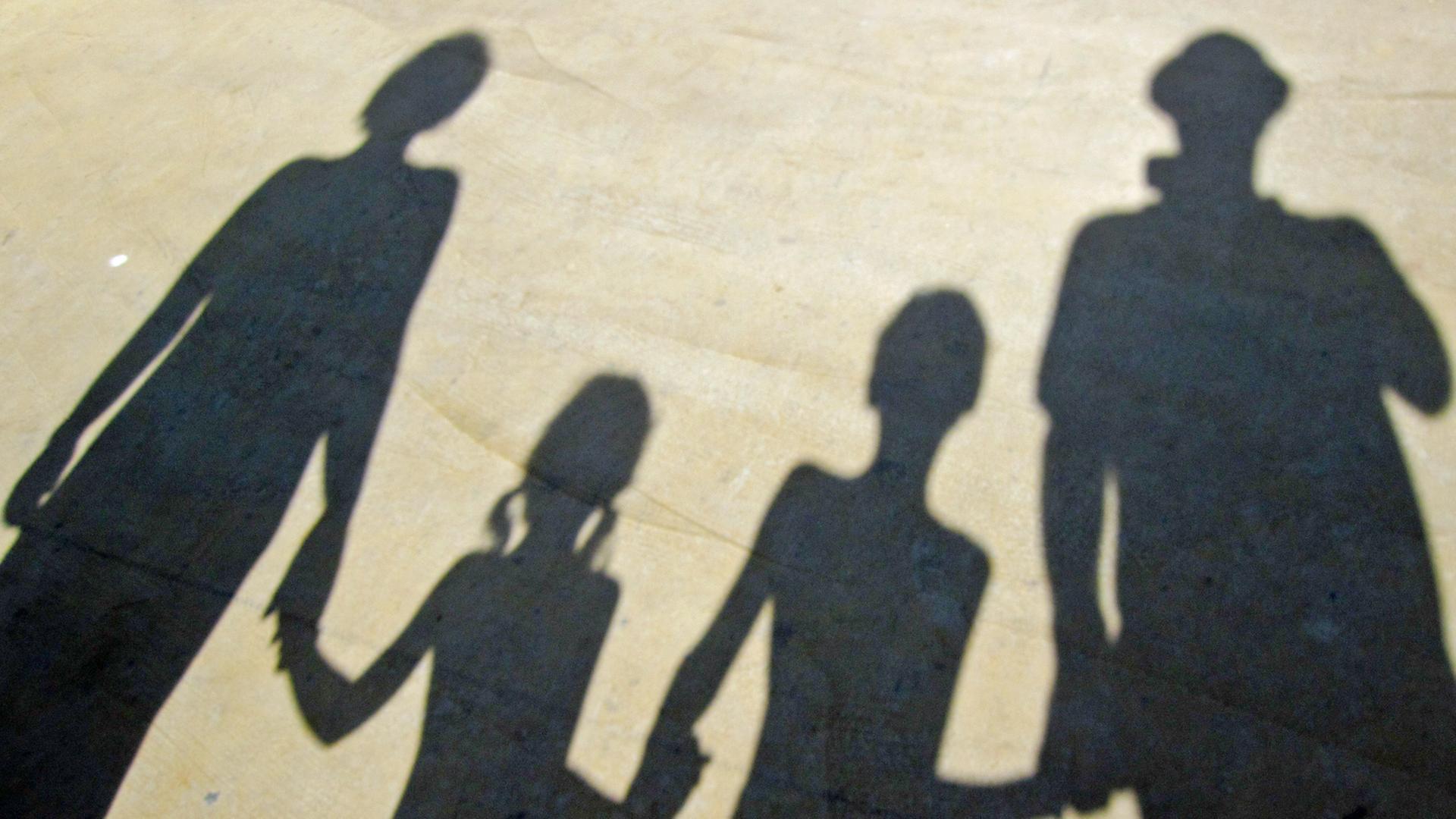 Der Schatten einer Familie, die sich an der Hand hält. Der Schatten einer Familie, die sich an der Hand hält.