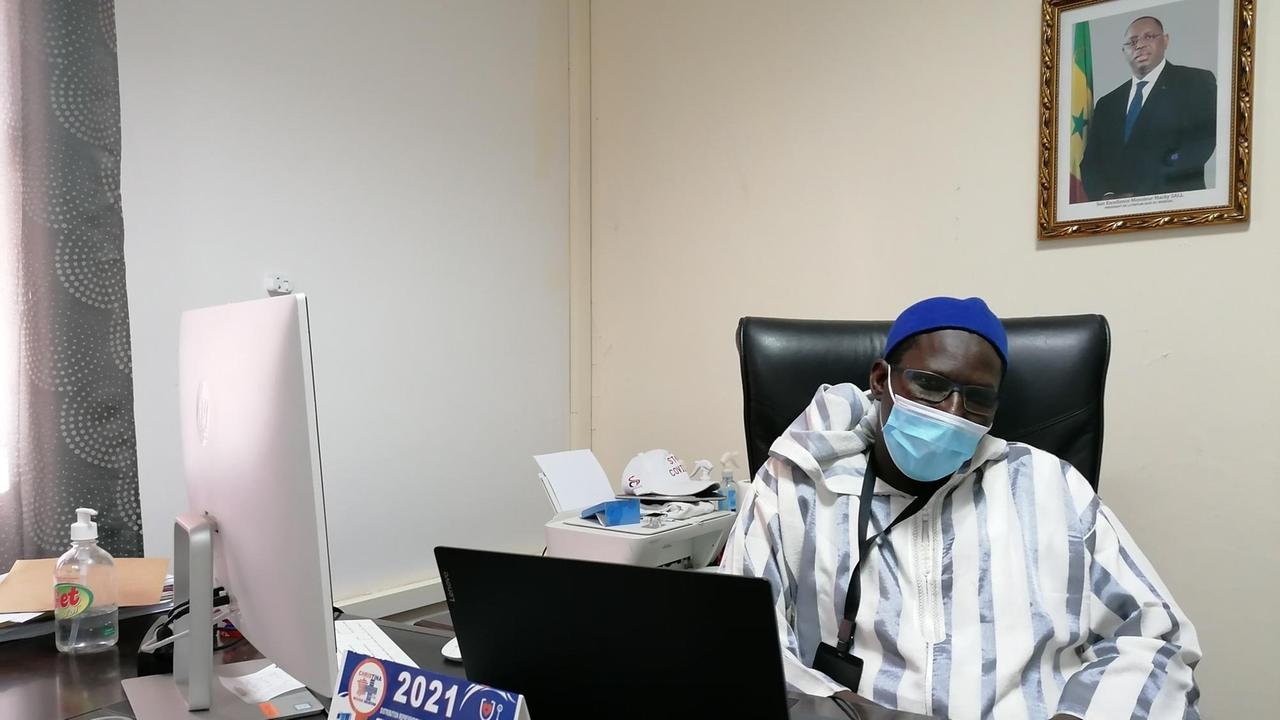 Doktor Mbaye leitet das Impfzentrum Kamara. An der Wand hängt ein Bild von Präsident Macky Sall.