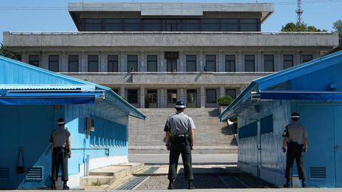 Drei Soldaten stehen in der militärischen Siedlung 'Panmunjeom' in der demilitarisierten Zone (DMZ) zwischen Nord- und Südkorea. Gesehen von Südkorea nach Nordkorea.