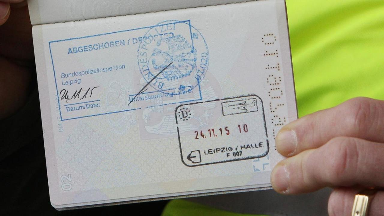 Ein Polizist zeigt den serbischen Pass eines abgelehnten Asylbewerbers mit dem Stempel "Abgeschoben" auf dem Flughafen Leipzig-Halle.