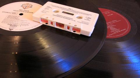 ILLUSTRATION - Eine Audio-Kompaktkassette (Musikkassette, MC, Audiokassette) liegt am 12.12.2014 in Berlin auf zwei Vinyl-Schallplatten (Langspielplatten, LP). Die mit einem Magnetband ausgerüstete Kassette, die in den 1970er Jahren bis in die 1990er Jahre hinein weit verbreitet war, wurde in einem Kassettenrekorder abgespielt und ermöglichte erstmals den mobilen Konsum von Musik. Beide Tonträger haben mit der Einführung der digitalen Audiotechnik der CD (Kompaktdisc) an Bedeutung verloren. Foto: Peter Zimmermann | Verwendung weltweit