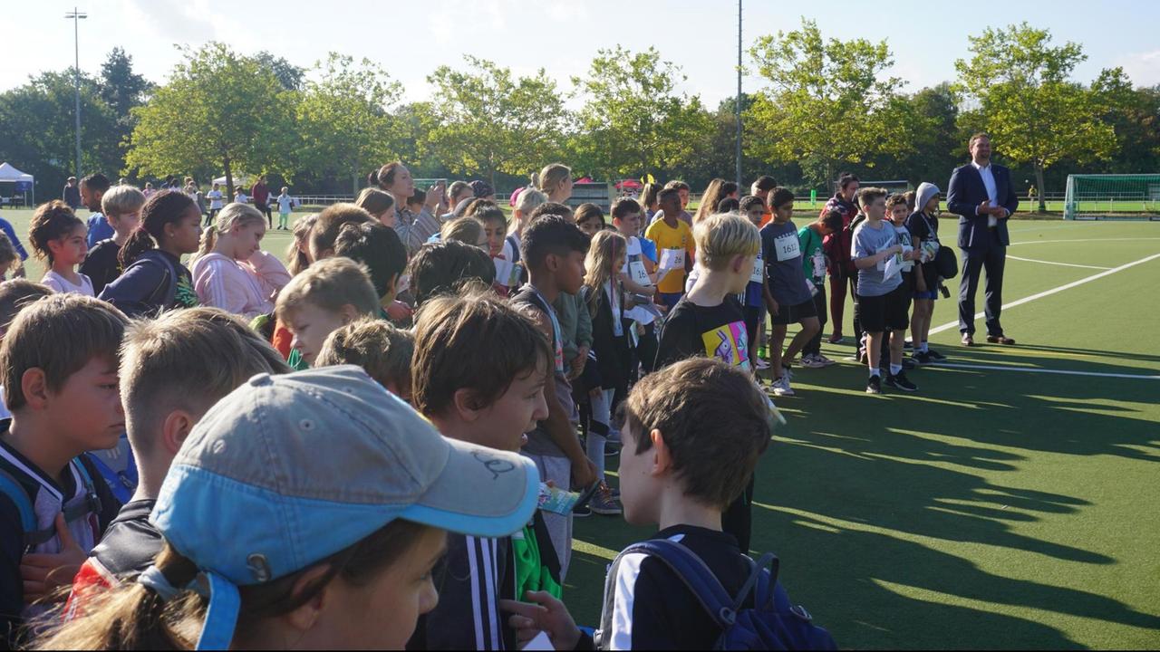 Eine Gruppe von Kindern steht auf einem Sportplatz, zusammen mit Gregor Kempert, Schul- und Sportamtsleiter Spandau. Eine Gruppe von Kindern steht auf einem Sportplatz, zusammen mit Gregor Kempert, Schul- und Sportamtsleiter Spandau.