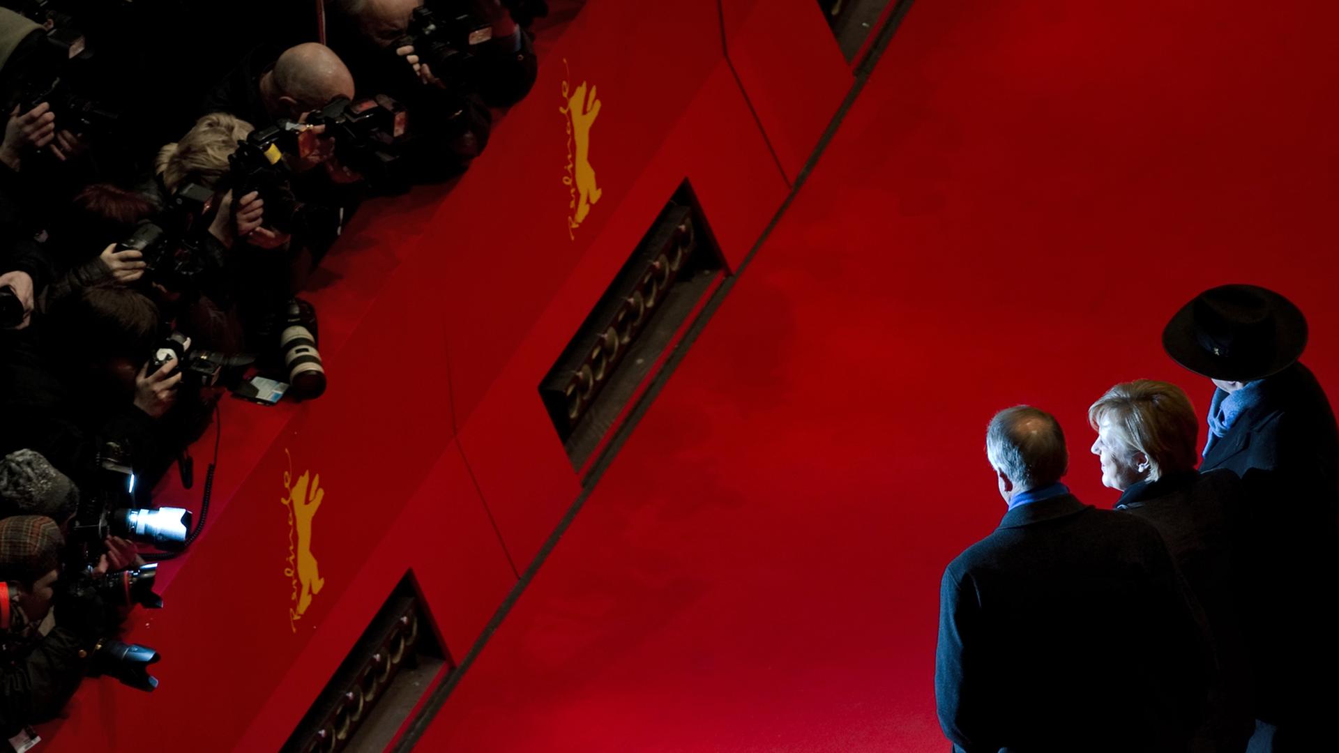 Berlinale-Direktor Dieter Kosslick (r.) steht mit Bundeskanzlerin Angela Merkel und dem damaligen Kulturstaatsminister Bernd Neumann am 13. Februar 2011 vor der Premiere des Films "Pina" auf dem Roten Teppich der 61. Berlinale.