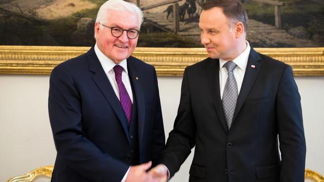 Das Bild zeigt Bundespräsident Steinmeier, wie er in Warschau von Polens Staatschef Duda empfangen wird. Im Weißen Saal des Präsidialpalastes geben sie sich die Hand.
