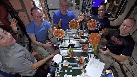 Das NASA-Bild zeigt die Astronauten Marke Vande Hei aus den USA (l-r), Sergei Rjasanski aus Russland, Paolo Nespoli aus Italien, Joe Acaba aus den USA und Randy Bresnik aus den USA, die auf der Internationalen Raumstation (ISS) ihre selbstgemachten Pizzen zeigen.