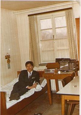 Der Vater von Publizist Martin Hyun liegt mit Anzug und Krawatte auf einem schmalen Bett.
