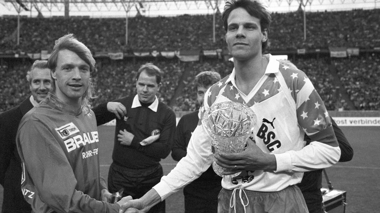 Die beiden Mannschaftskapitäne geben sich vor Beginn des innerstädtischen "Fußball-Gipfels" zwischen Hertha BSC und Union Berlin am 27.01.1990 im Olympiastadion in Berlin die Hand. Die beiden Mannschaftskapitäne geben sich vor Beginn des innerstädtischen "Fußball-Gipfels" zwischen Hertha BSC und Union Berlin am 27.01.1990 im Olympiastadion in Berlin die Hand.