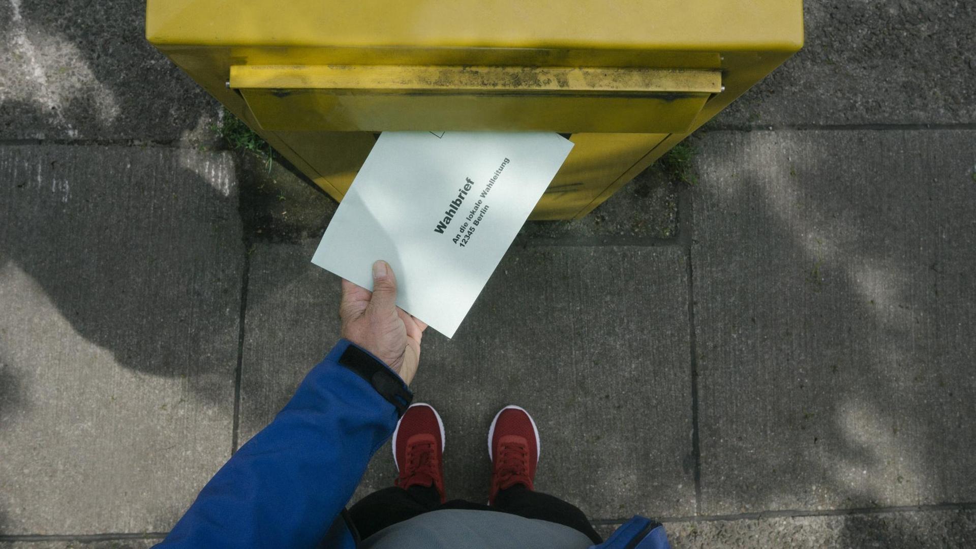 Eine Person wirft einem Wahlbrief in einen Briefkasten