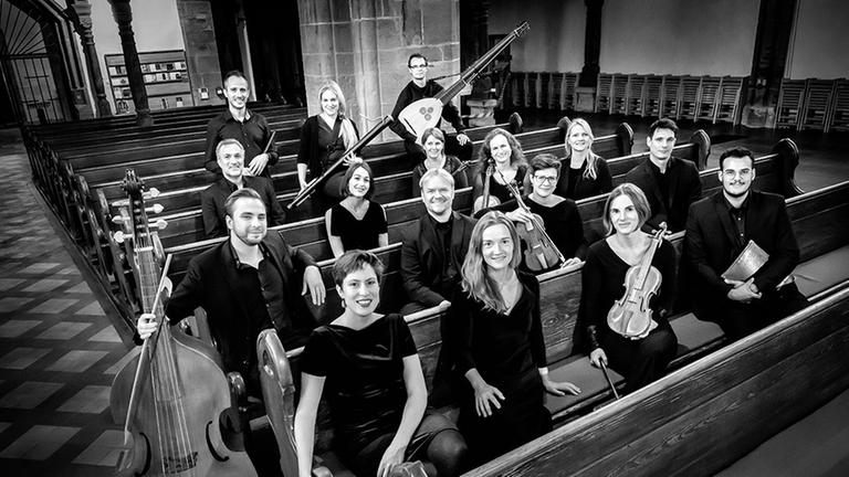 Die Musiker sitzen und stehen mit ihren Instrumenten in einem Kirchengestühl. Die Musiker sitzen und stehen mit ihren Instrumenten in einem Kirchengestühl.