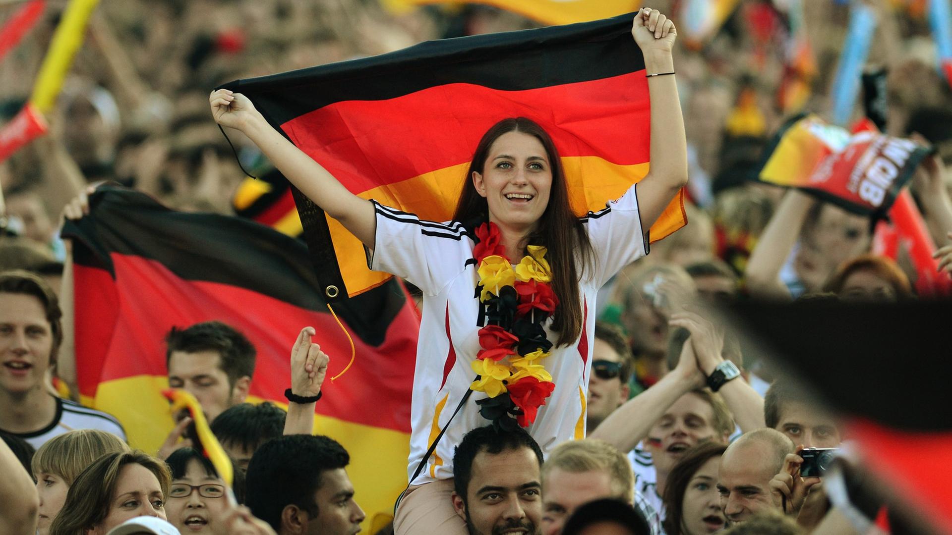 Deutsche Fußball-Fans schwenken auf der Fanmeile vor dem Brandenburger Tor Deutschlandfahnen Deutsche Fußball-Fans schwenken auf der Fanmeile vor dem Brandenburger Tor Deutschlandfahnen
