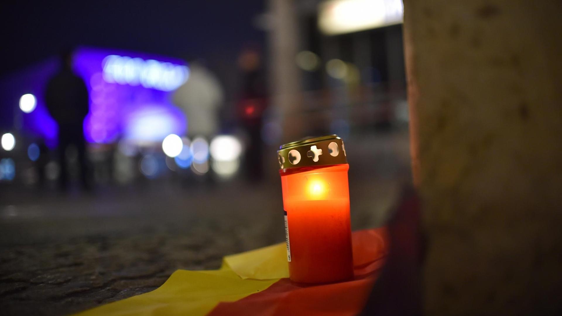 Ein Grablicht steht auf einer deutschen Fahne zum Gedenken an die Opfer vor dem Weihnachtsmarkt an der Gedächtniskirche in Berlin. Ein Grablicht steht auf einer deutschen Fahne zum Gedenken an die Opfer vor dem Weihnachtsmarkt an der Gedächtniskirche in Berlin.