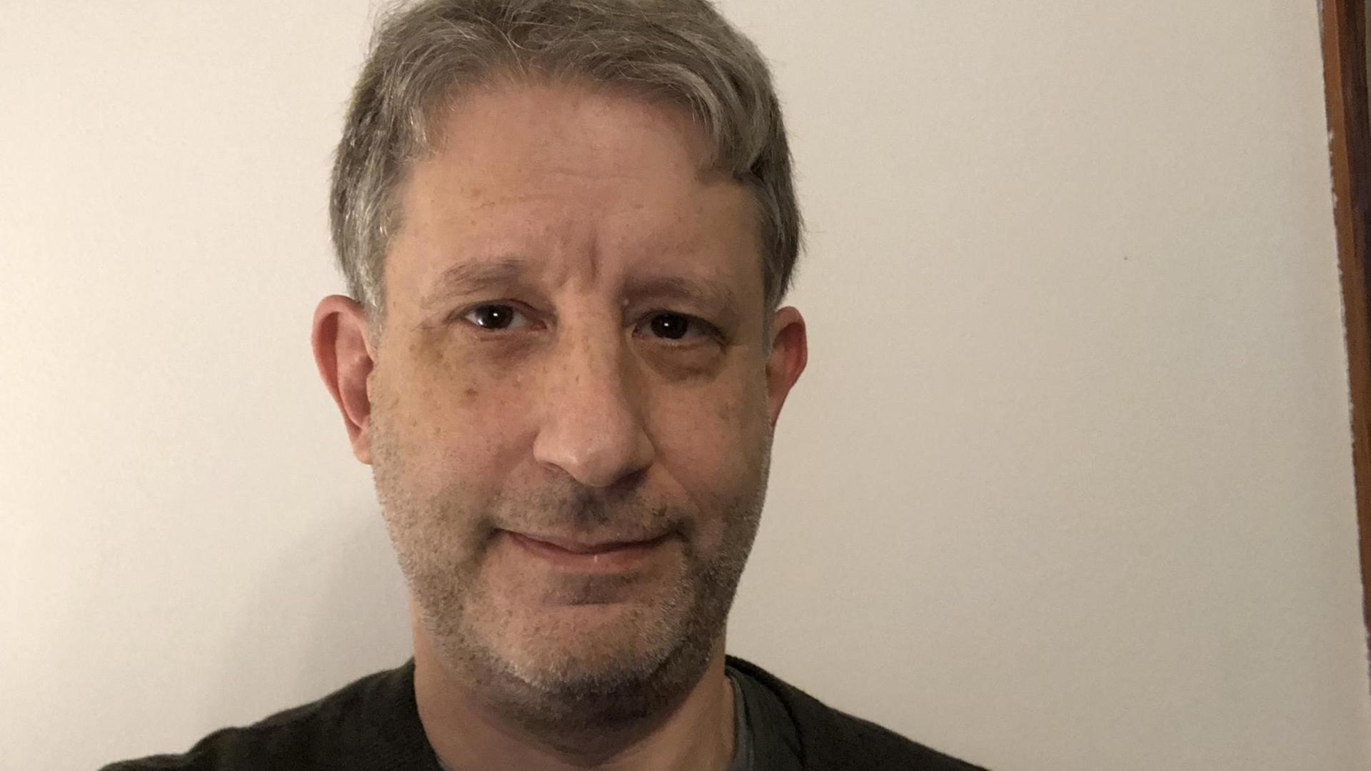 Auf dem Foto ist der Medienwissenschaftler David Golumbia zu sehen. Er lächelt freundlich in die Kamera. Auf dem Foto ist der Medienwissenschaftler David Golumbia zu sehen. Er lächelt freundlich in die Kamera.