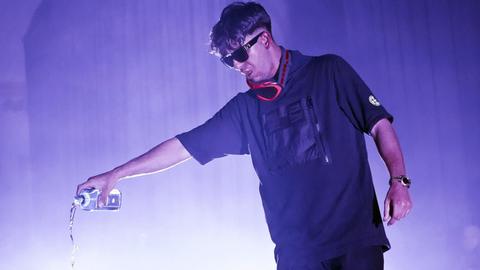 Rapper Ufuk Bayraktar aka Ufo361 steht bei einem Konzert in Huxleys in Berlin auf der Bühne. Er ist in dunklen Farben gekleidet und trägt eine Sonnenbrille.