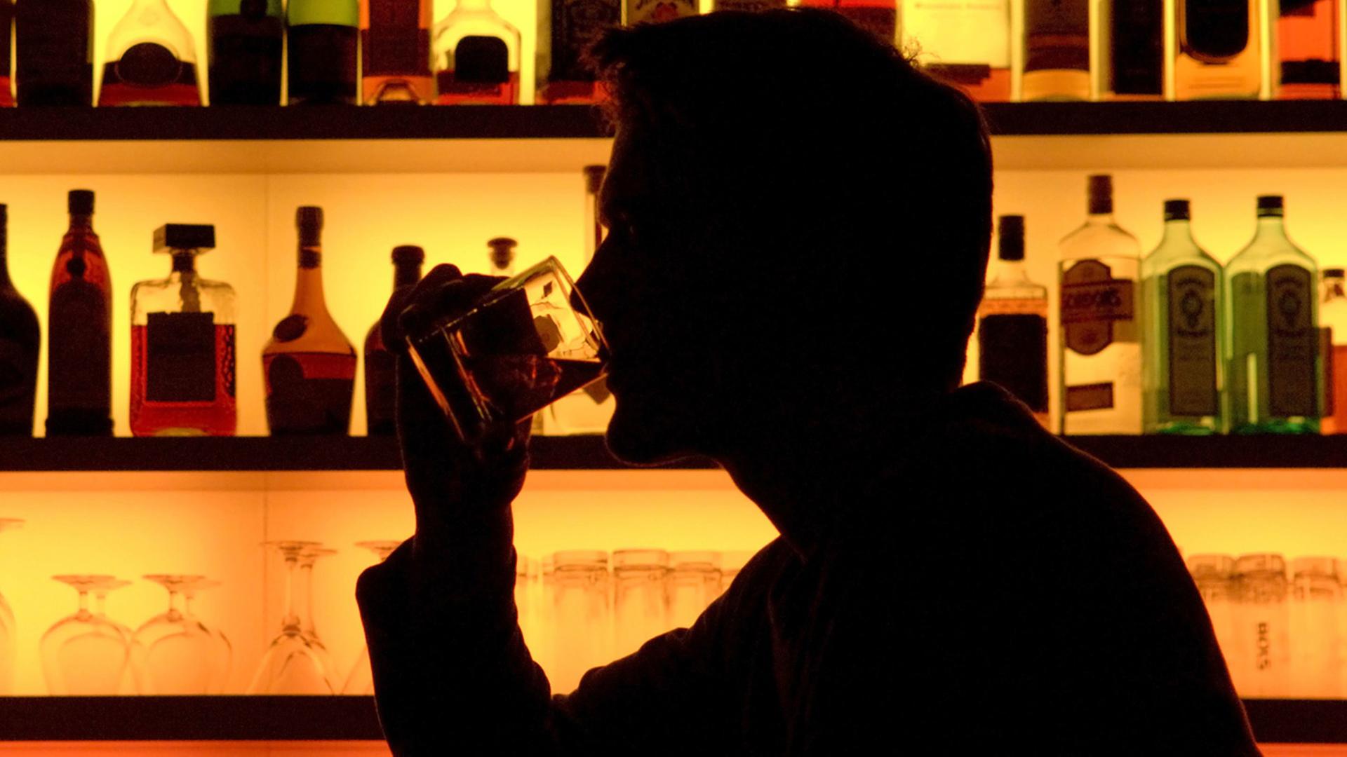Ein Bar-Besucher trinkt ein Glas Whiskey Ein Bar-Besucher trinkt ein Glas Whiskey