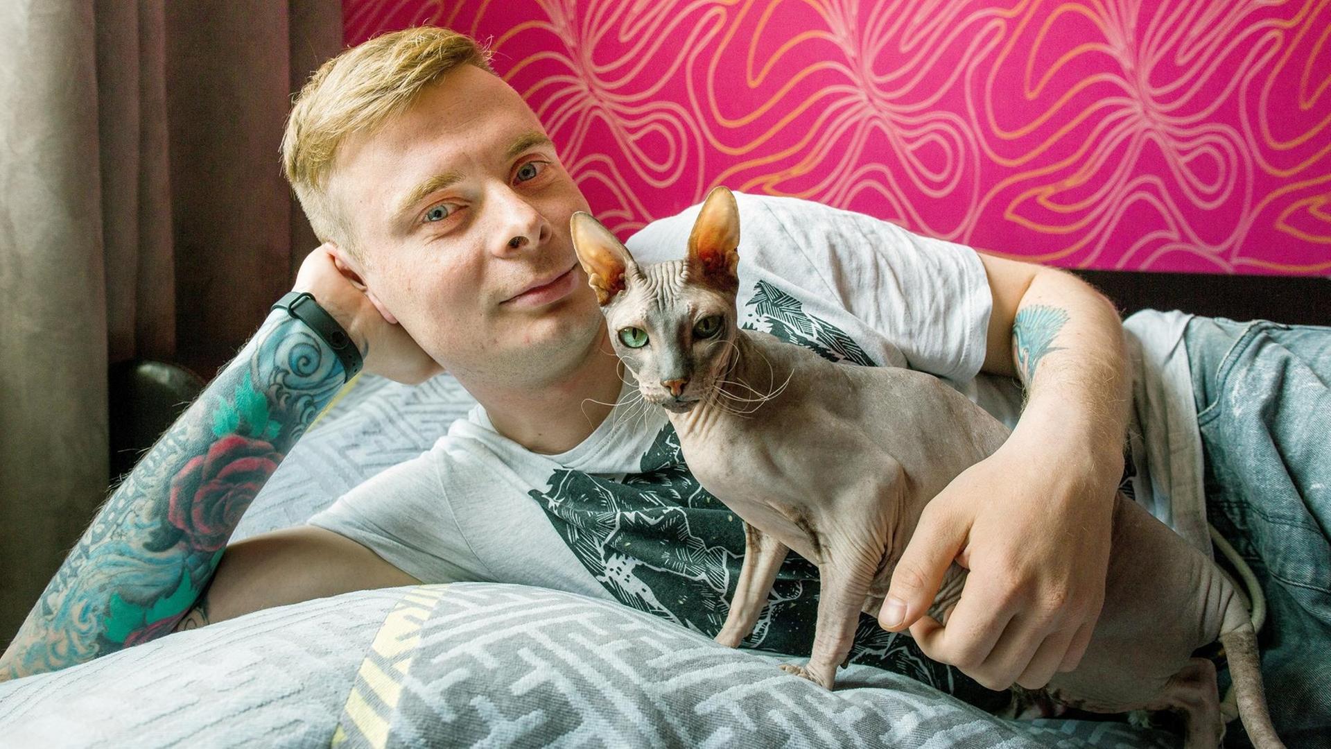 Junger Mann und eine Katze liegen auf einem Bett. Szene aus der Doku "24h Europe - The Next Generation" Junger Mann und eine Katze liegen auf einem Bett. Szene aus der Doku "24h Europe - The Next Generation"