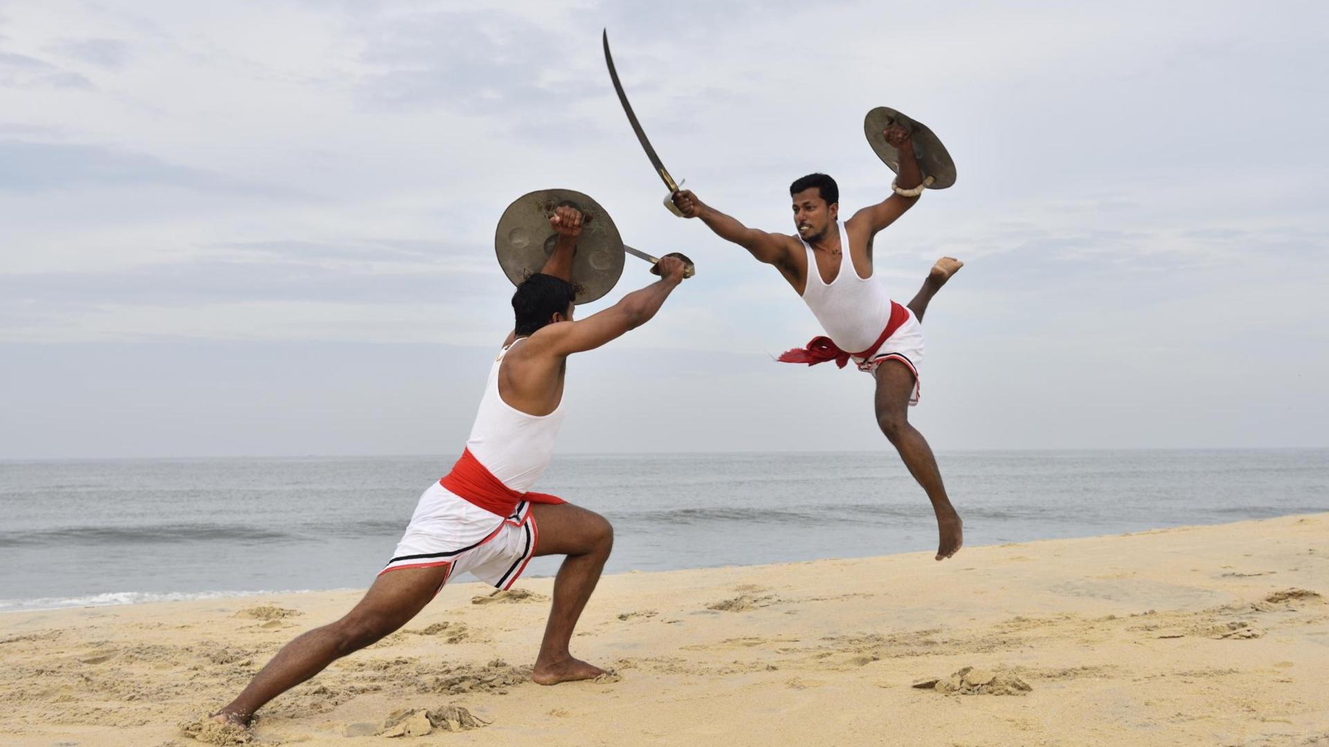 Zwei Kalaripayattu Kämpfer mit langen Säbeln und runden Schildern in Aktion