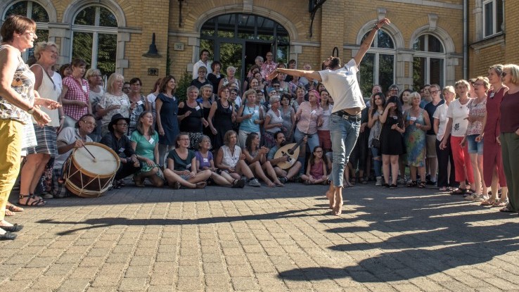 In einem Halbkreis von Singenden tanzt ein junger Mann In einem Halbkreis von Singenden tanzt ein junger Mann