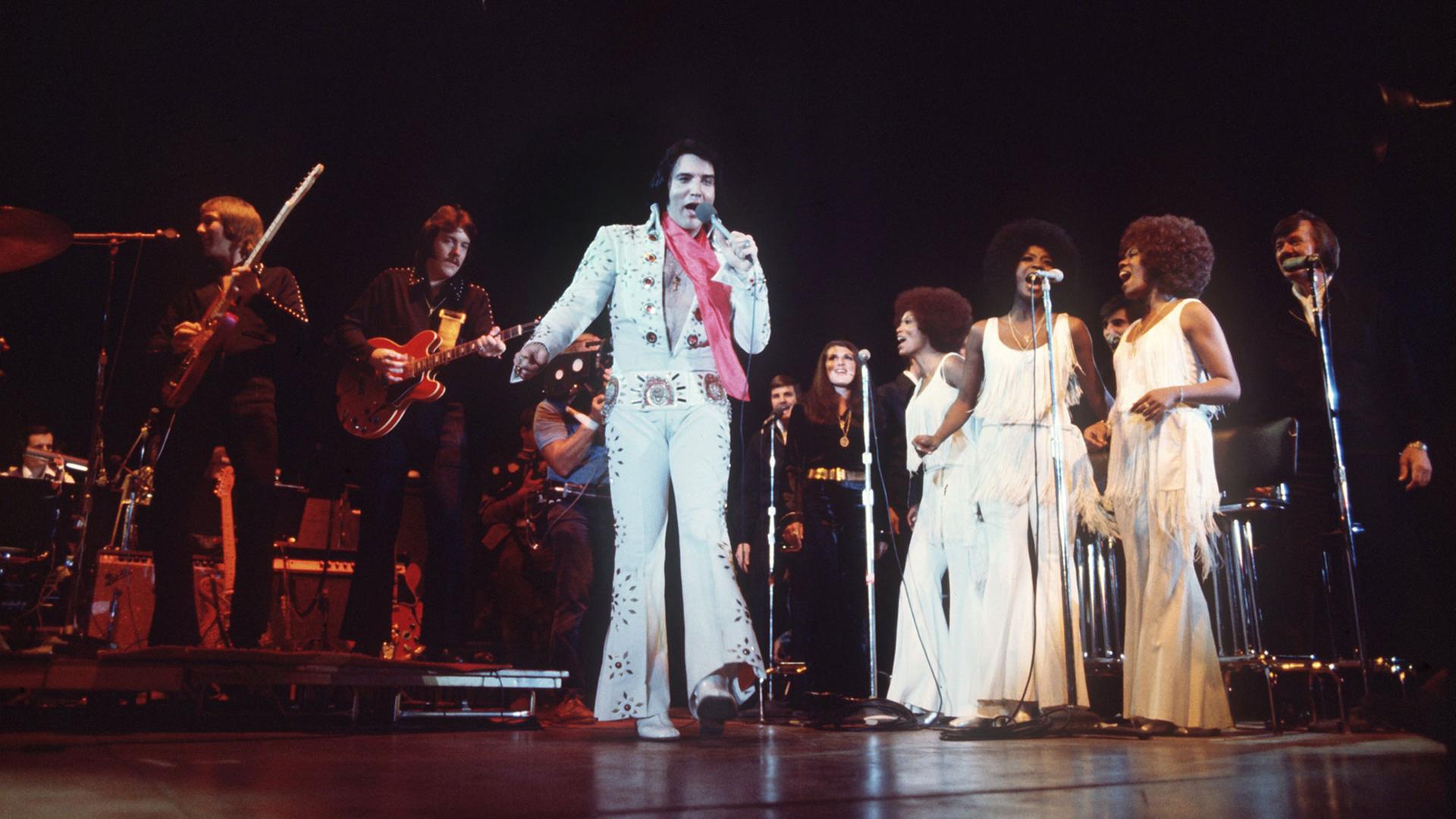 Begleitet von einer Band und Hintergrund-Sängerinnen tritt das US-amerikanische Rock-Idol Elvis Presley in Las Vegas/Nevada auf. Undatierte Aufnahme. Begleitet von einer Band und Hintergrund-Sängerinnen tritt das US-amerikanische Rock-Idol Elvis Presley in Las Vegas/Nevada auf. Undatierte Aufnahme.