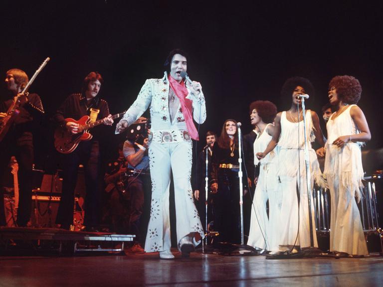 Begleitet von einer Band und Hintergrund-Sängerinnen tritt das US-amerikanische Rock-Idol Elvis Presley in Las Vegas/Nevada auf. Undatierte Aufnahme.
