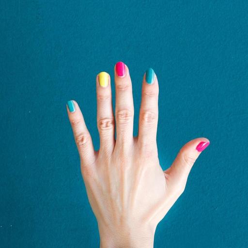 Eine Hand mit buntlackierten Fingernägeln vor blauem Hintergrund.
